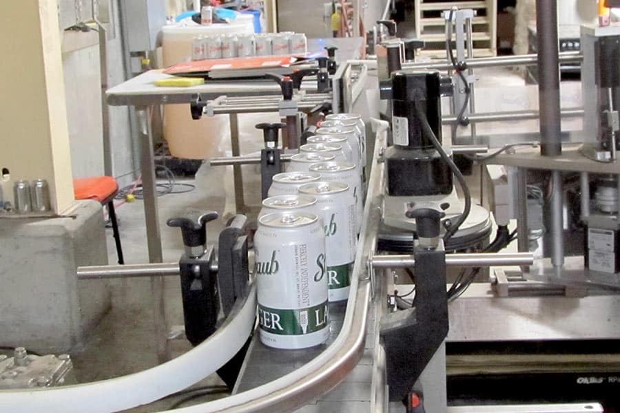 Filled cans of beer coming off filling line at brewery