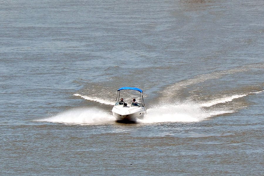 White speed boat crosses large river